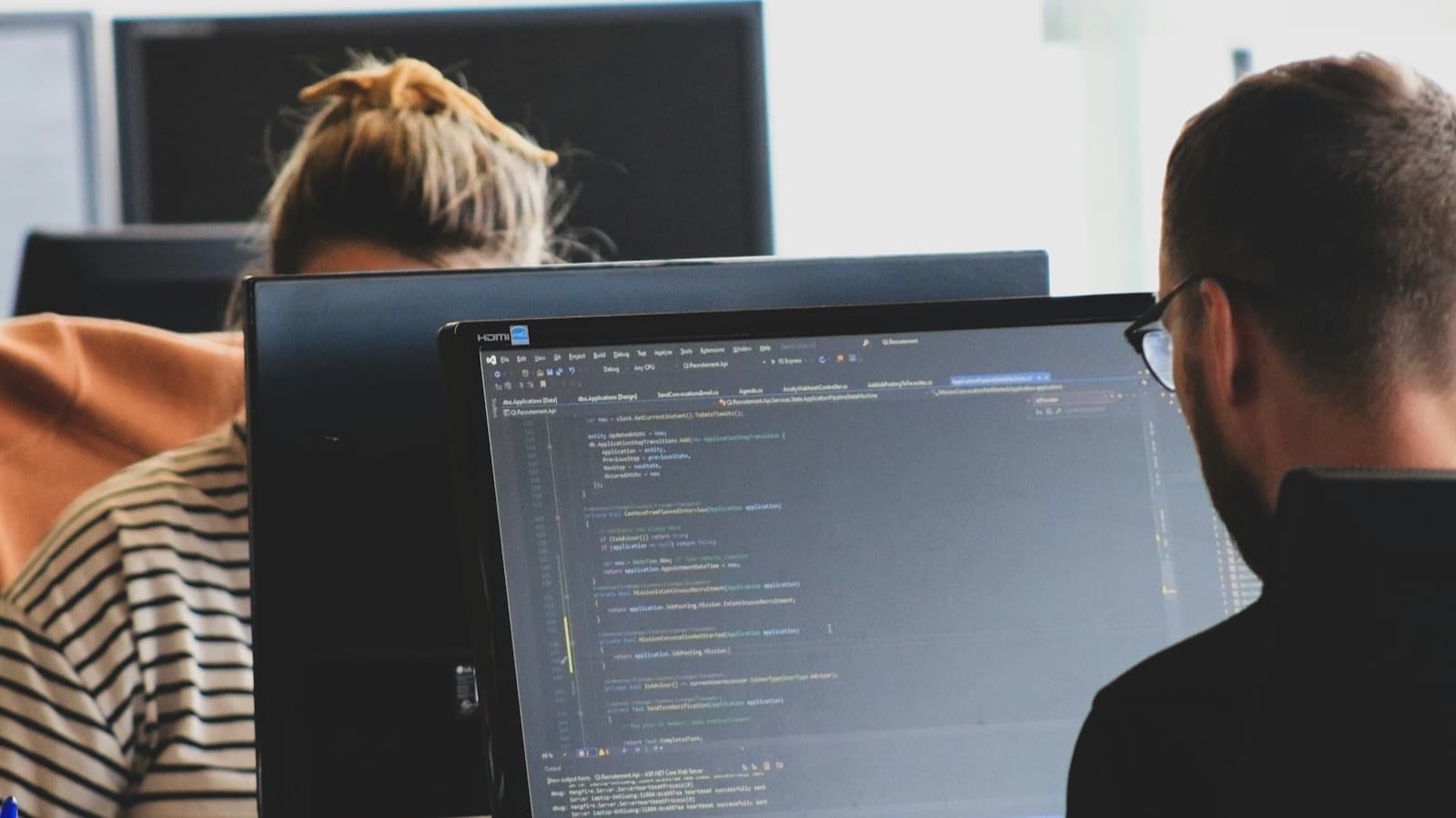 Two developers working on code at their monitors